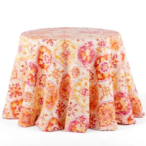 An Ali Tangerine linen rental with a round table covered in orange and pink floral fabric.