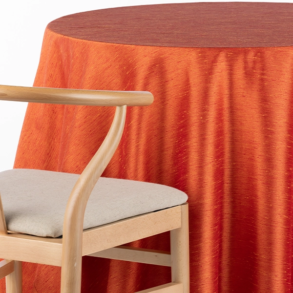 A chair next to the table with Tussah Sunset Orange Red table linen rental