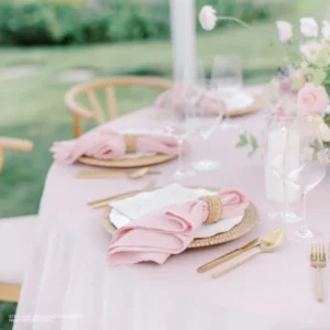 A luxurious table setting with event linen rental, featuring pink table linens and gold flatware and Callie Dusty Rose Napkins.