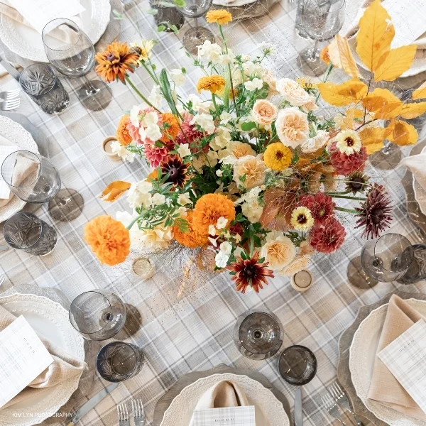 A beautifully set table with glasses and flowers, showcasing the elegance of Weston Wheat Plaid event linen rental.