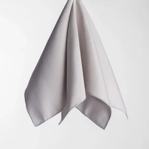 A sophisticated Monaco Moonstruck cloth napkin with a subtle texture hangs against a plain white background.