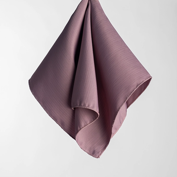 The Monaco Woodrose handkerchief, in an elegant mauve color with a subtle texture, is draped and suspended against a plain white background.