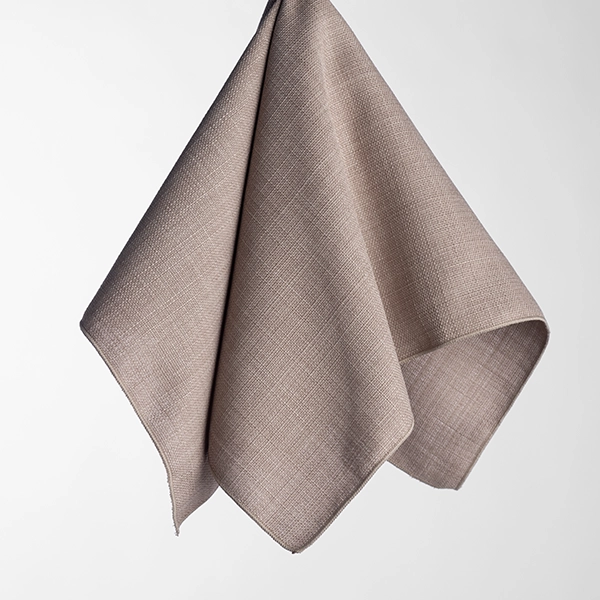 The Nola Stone, a beige linen cloth featuring a subtle textured pattern, is hanging against a plain white background.