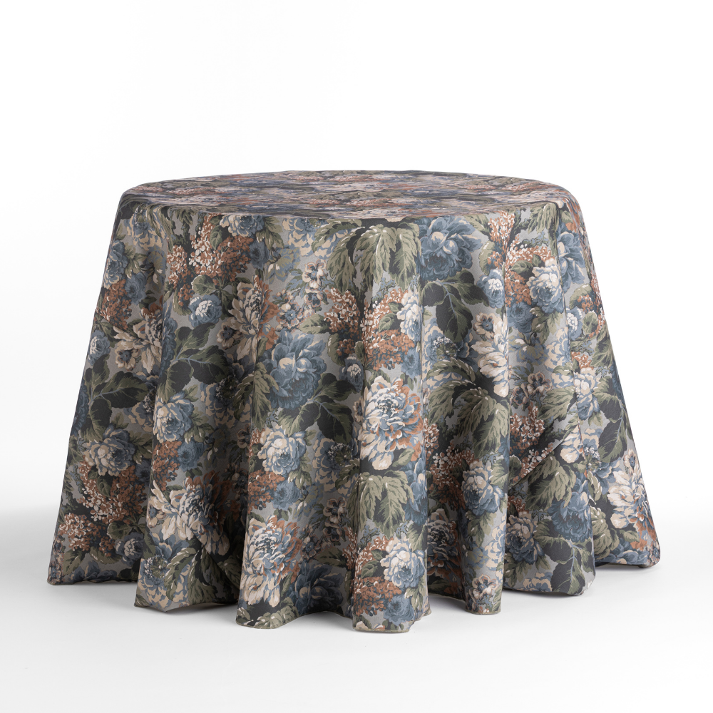 The Cafe Noir Velvet features a draped, floral-patterned cloth with blue, green, and peach hues on a white background covering the round table.