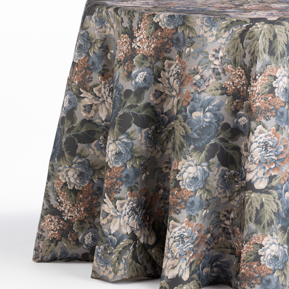 A Cafe Noir Velvet tablecloth with floral patterns of large flowers and green leaves covers the round table.