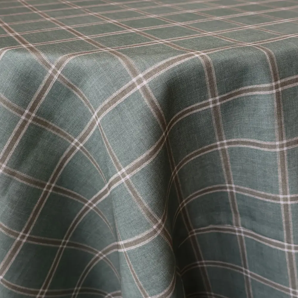 Close-up of a table draped with Rustic Moss Plaid fabric, featuring a green base adorned with white and brown lines.