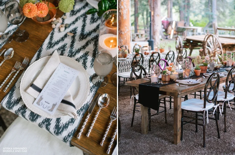 A rustic outdoor dining setup with wooden tables, patterned runners, floral centerpieces, and black chairs. One table setting includes a plate with napkin and menu card. Candles are also placed on tables.