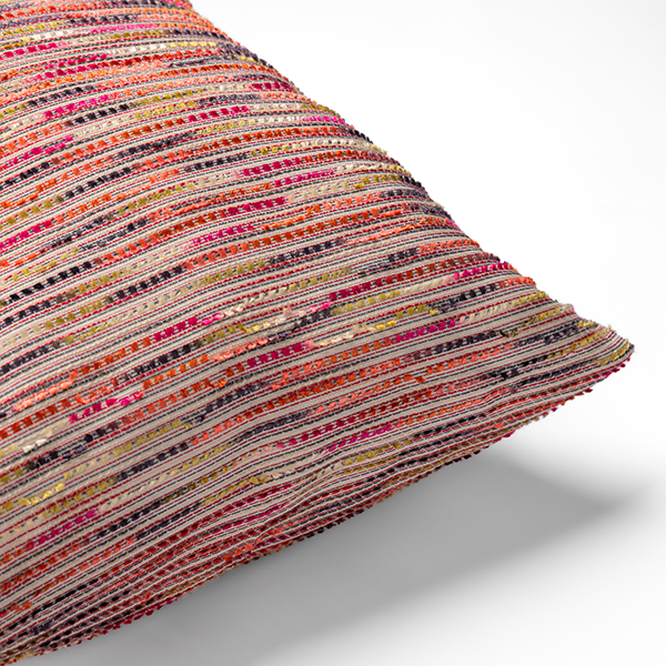 A close-up view of a colorful, striped cushion with a mix of red, orange, yellow, and purple threads.