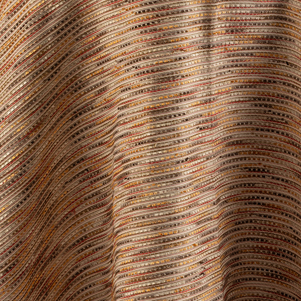 Close-up of a fabric with horizontal, multicolored stripes in shades of brown, orange, yellow, and red. The material appears textured and woven.