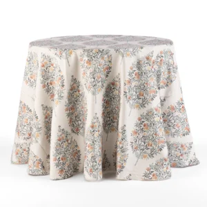 A round table covered with a draped, floral-patterned tablecloth featuring orange and grey flowers against a light background.