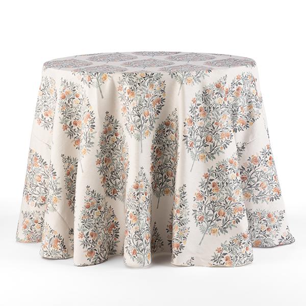 A round table covered with a draped, floral-patterned tablecloth featuring orange and grey flowers against a light background.