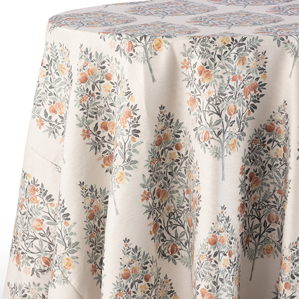 A round table covered with a white tablecloth featuring a repeating pattern of stylized orange trees with green leaves and orange fruits.