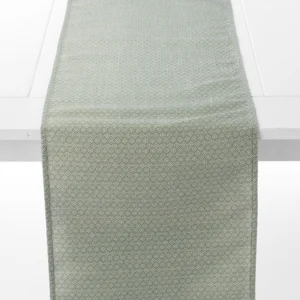 A light green table runner with a subtle geometric pattern is placed on a white table.