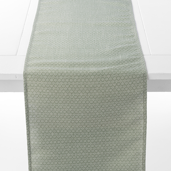 A light green table runner with a subtle geometric pattern is placed on a white table.