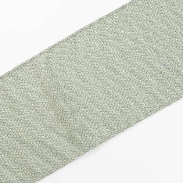 A pale green fabric with a repeating small geometric pattern is spread out flat against a white background.