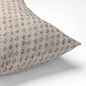 A beige pillow with a pattern of small, tree-like motifs in white and brown.