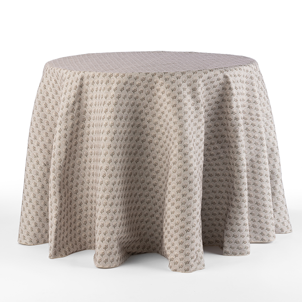 A round table draped with a beige patterned tablecloth against a white background.