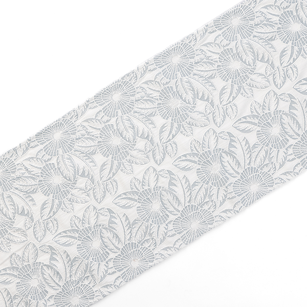 A white fabric with an intricate floral pattern in light grey spanning its surface, arranged in a diagonal orientation.