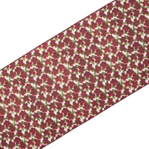 A fabric with a pattern of small red and green flowers on a white background is shown diagonally.