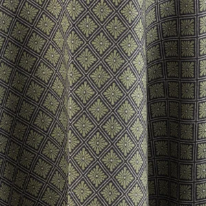 Close-up of fabric with a diamond pattern, each containing a small floral design, in shades of green and black.