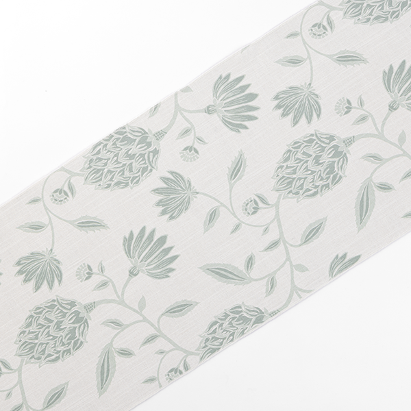 A piece of fabric with a light gray background featuring a pattern of green floral designs and leaves.