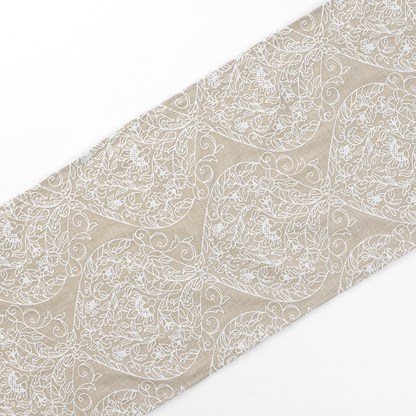 A piece of fabric with a beige and white floral pattern arranged in a repetitive geometric design is shown. The pattern features intricate, symmetrical swirls and flowers.