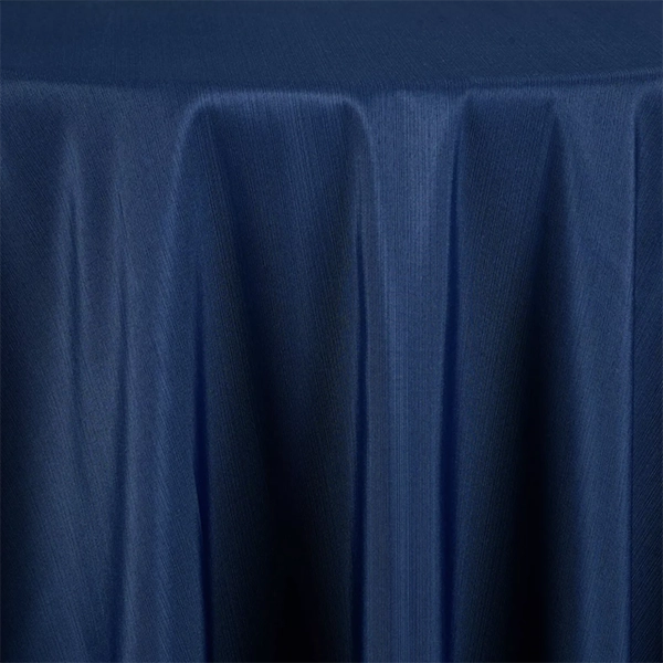 The Monaco Navy draped tablecloth, featuring a slightly glossy texture, covers a round table.