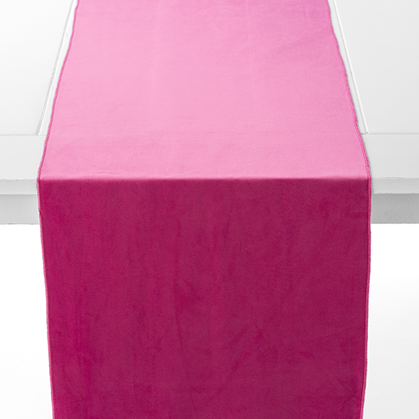 A white table with a bright pink table runner draped over the middle.