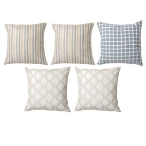 Five decorative pillows with different patterns: three with stripes, one with a square grid, and one with a geometric design in neutral colors.