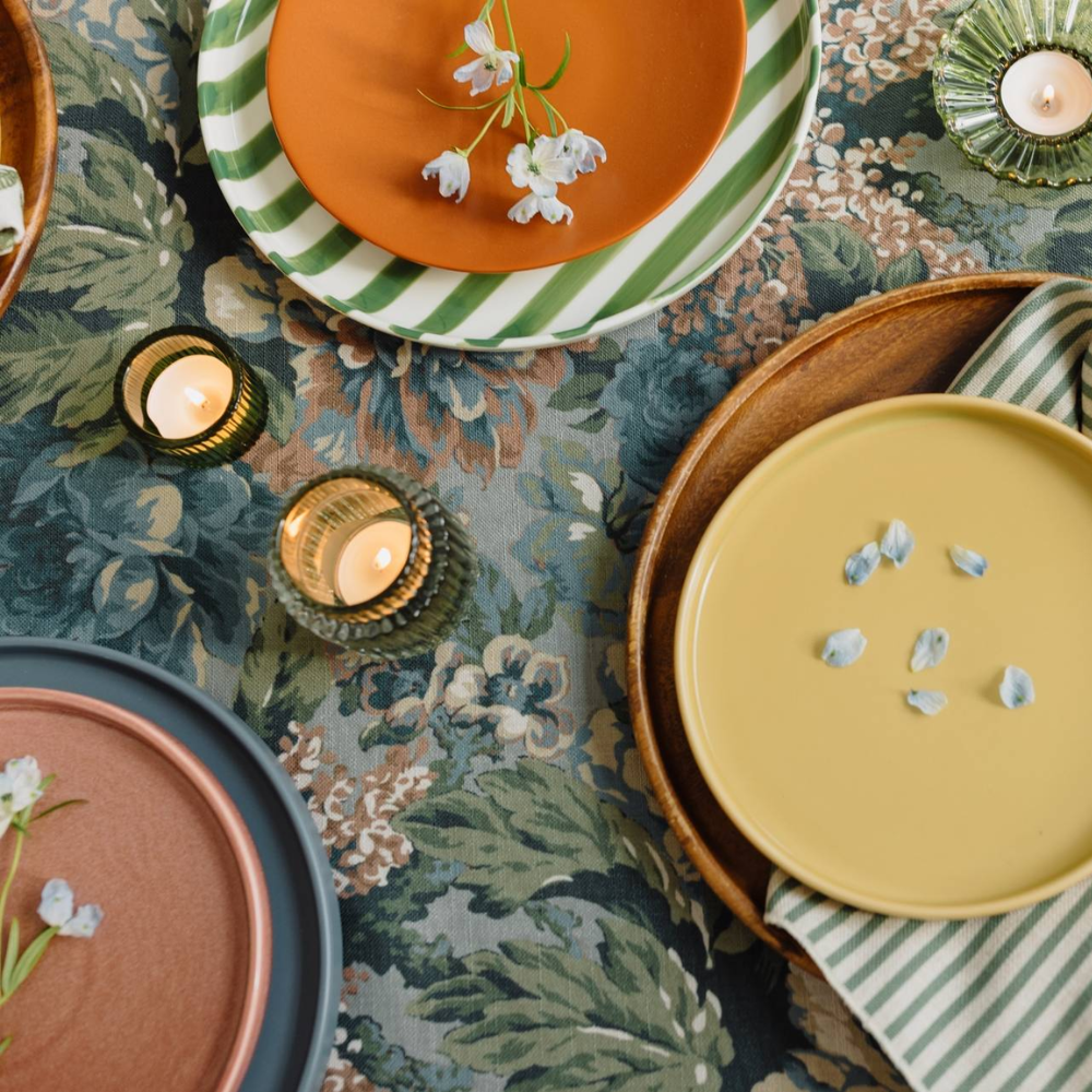 Roxy Rainbow Metallic plates adorned with small flowers and lit candles on a floral tablecloth.